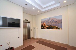 Ein modernes Interieur mit einem Flachbildfernseher, einem Aufzug und einem Gemälde einer Berglandschaft.