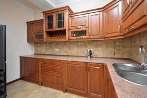A kitchen with wooden cabinets, a granite countertop, a stainless steel sink, and a coffee maker. - Apartment by Luxe Group AB917 (Yerevan)