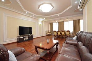A spacious living room with a large flat-screen TV, leather sofas, a wooden coffee table, and a dining area with chairs. - Apartment by Luxe Group AB917 (Yerevan)