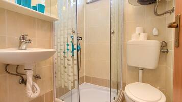 Ein Badezimmer mit Duschkabine, Waschbecken und Toilette.