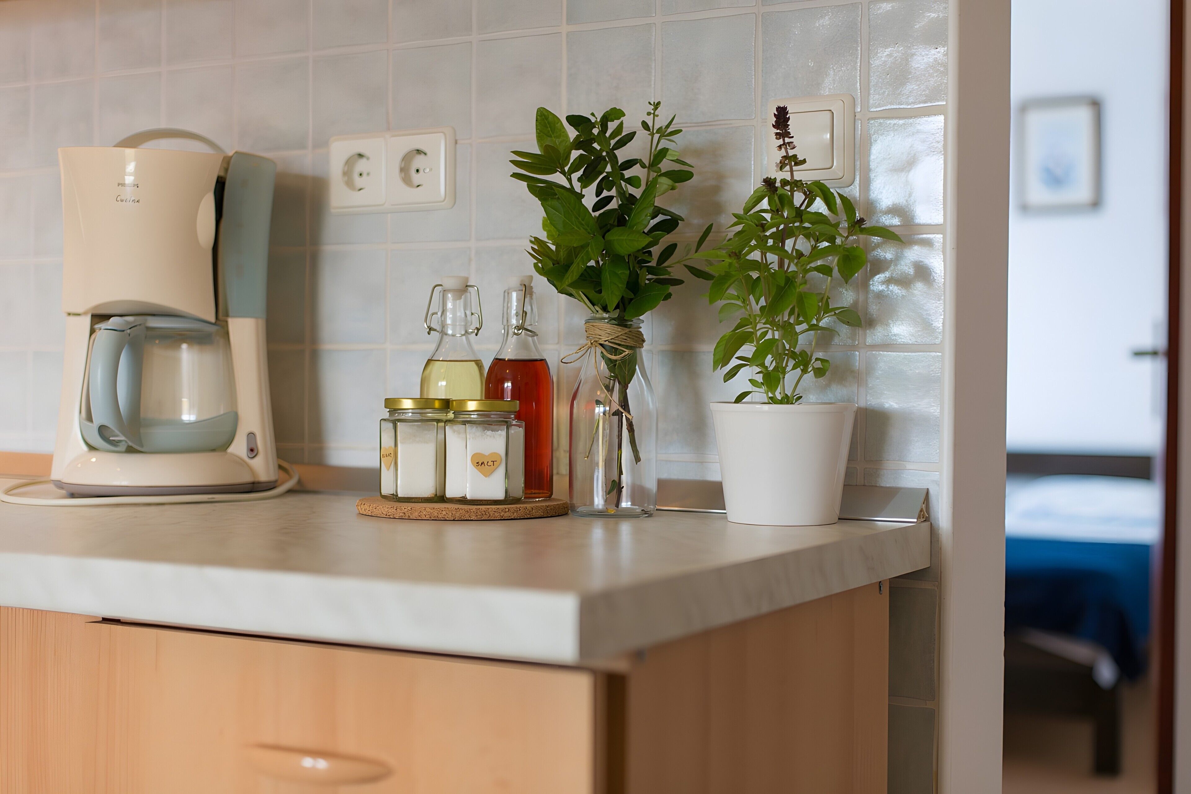 Een keukenblad met een koffiezetapparaat, zout- en peperstel en planten in potten.