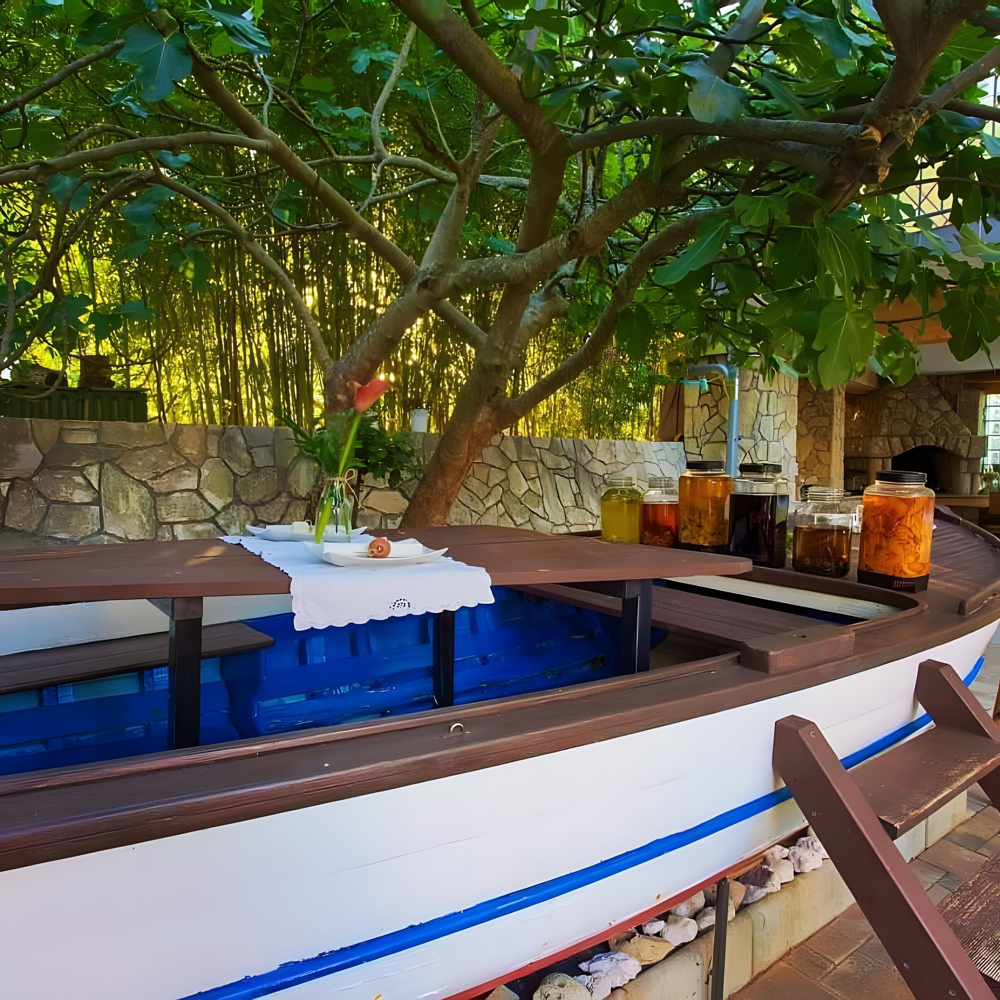 Una piscina con forma de barco, con un muro de piedra y una chimenea de piedra al fondo.
