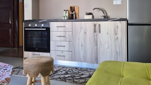 A modern kitchen with wooden cabinets, a built-in oven, and a stainless steel refrigerator. - Mokshouse – Bright, Comfortable Apartment near City Center and Beach (Kavala)