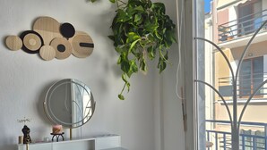 A modern bathroom with a white vanity, a round mirror, a hanging plant, and a view of the outside balcony. - Mokshouse – Bright, Comfortable Apartment near City Center and Beach (Kavala)
