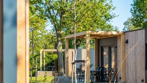 Een houten hut met een overdekt terras, stenen muren en uitzicht op de omgeving.
