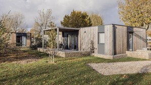 Een modern, gelijkvloers huis met een stenen fundering, een houten gevel en een overdekt buitengebied.