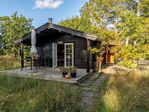 Eine rustikale Holzhütte mit überdachter Veranda, Schornstein und einer Tür zum Innenbereich.