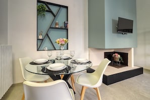 Een moderne eetruimte met een glazen tafel, witte stoelen, een zwart-wit geruit placemat en een decoratieve vaas.