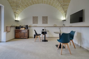 A modern kitchen with a stone ceiling, a flat-screen TV, and a dining area with chairs and a table.