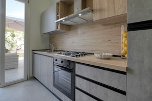 A modern kitchen with a built-in oven, a gas stove, and wooden cabinetry.