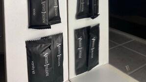 Een badkamer met witte wanden, een spiegel en toiletartikelen, waaronder zeep en shampooflessen.