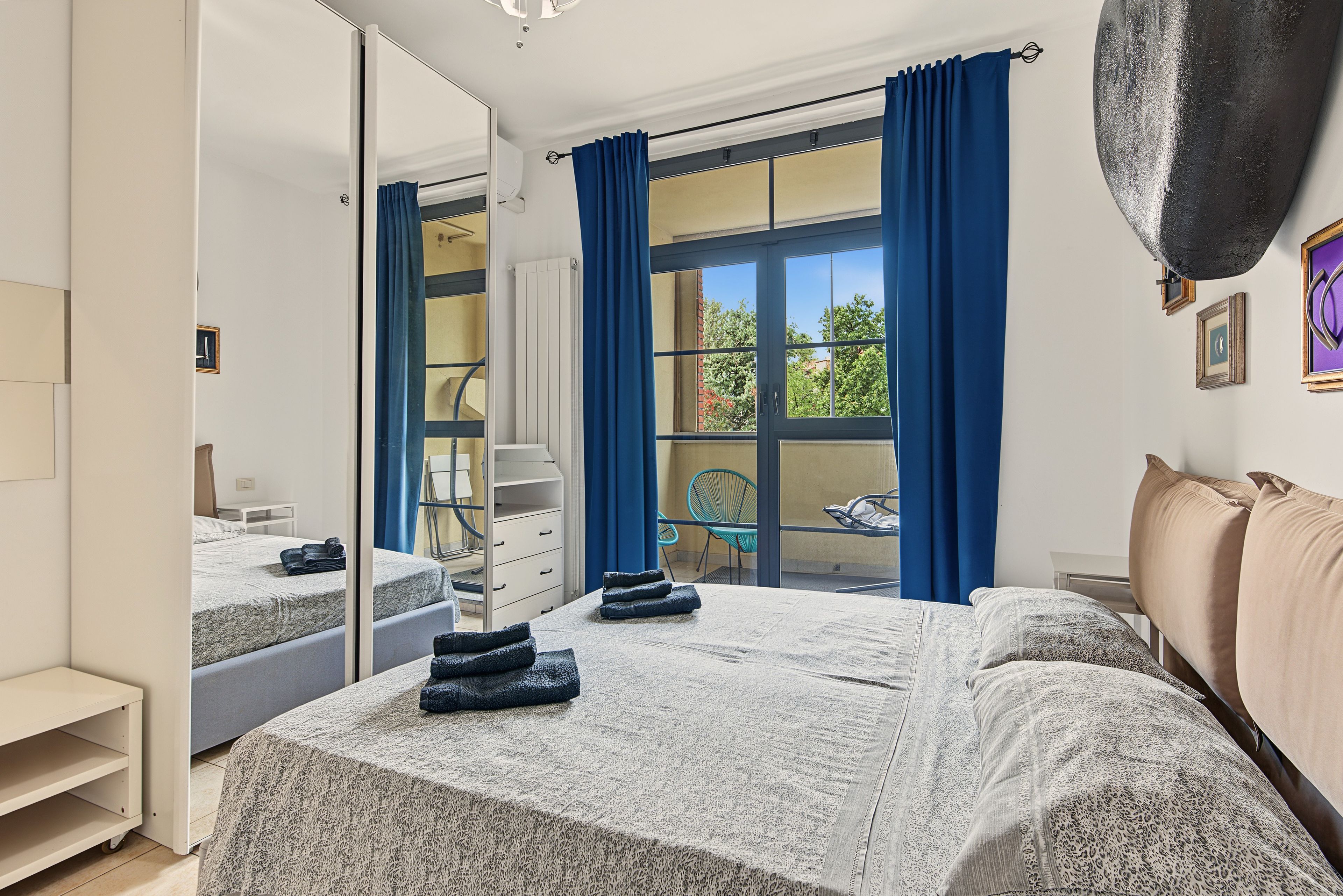 A hotel room with a bed, a chair, a desk, and a window with curtains.