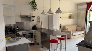 Eine moderne Küche mit einer zentralen Kochinsel, Barhocker und einer Essecke mit einer Couch.