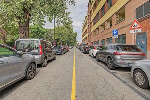 Een straat met geparkeerde auto's en een gebouw met een parkeerbord.