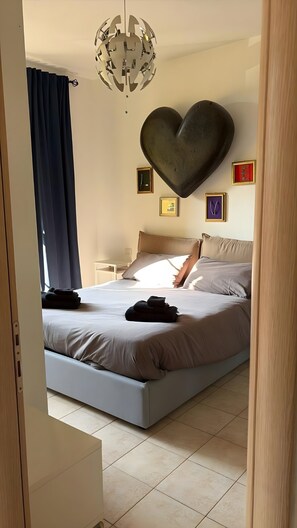 Ein modernes Schlafzimmer mit einem großen Bett, einer herzförmigen Wanddekoration und einem einzigartigen Kronleuchter.