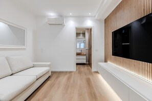 Un salon moderne avec un canapé, un téléviseur à écran plat et un mur recouvert de panneaux en bois.