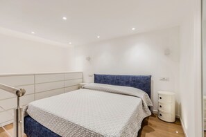 Um quarto moderno com uma cama, mesas de cabeceira e um criado-mudo.