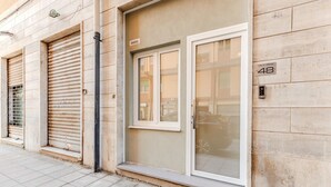 A building facade with closed shutters, a door with a glass panel, and a number '48' sign. - Cagliari Suite Monti Fly – Renovated Central Apartment Near San Benedetto Market (Cagliari)