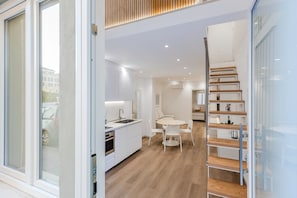 Ein modernes Interieur mit Küche, Essbereich und einer Treppe.