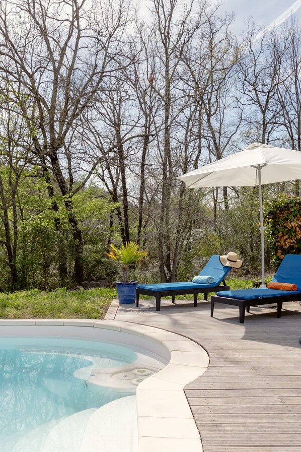 Een zwembadgedeelte met ligbedden, een parasol en een potplant.