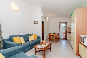 Un soggiorno con un divano blu, un tavolino in legno e un angolo cottura con forno a microonde.