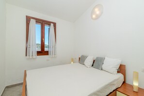 Un dormitorio con cama, cortinas, una mesita de noche y un aparador.