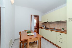 Una cucina compatta con tavolo, sedie, lavello e pensili.