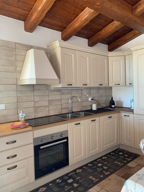 A kitchen with white cabinets, a stainless steel sink, a range hood, and a black oven. - Casa Marina Villasimius: Comfort, Relaxation, and Privacy, with Private Parking (Villasimius)