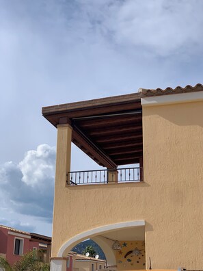 Ein Gebäude mit Balkon, Bogenportal und einem Berg im Hintergrund.