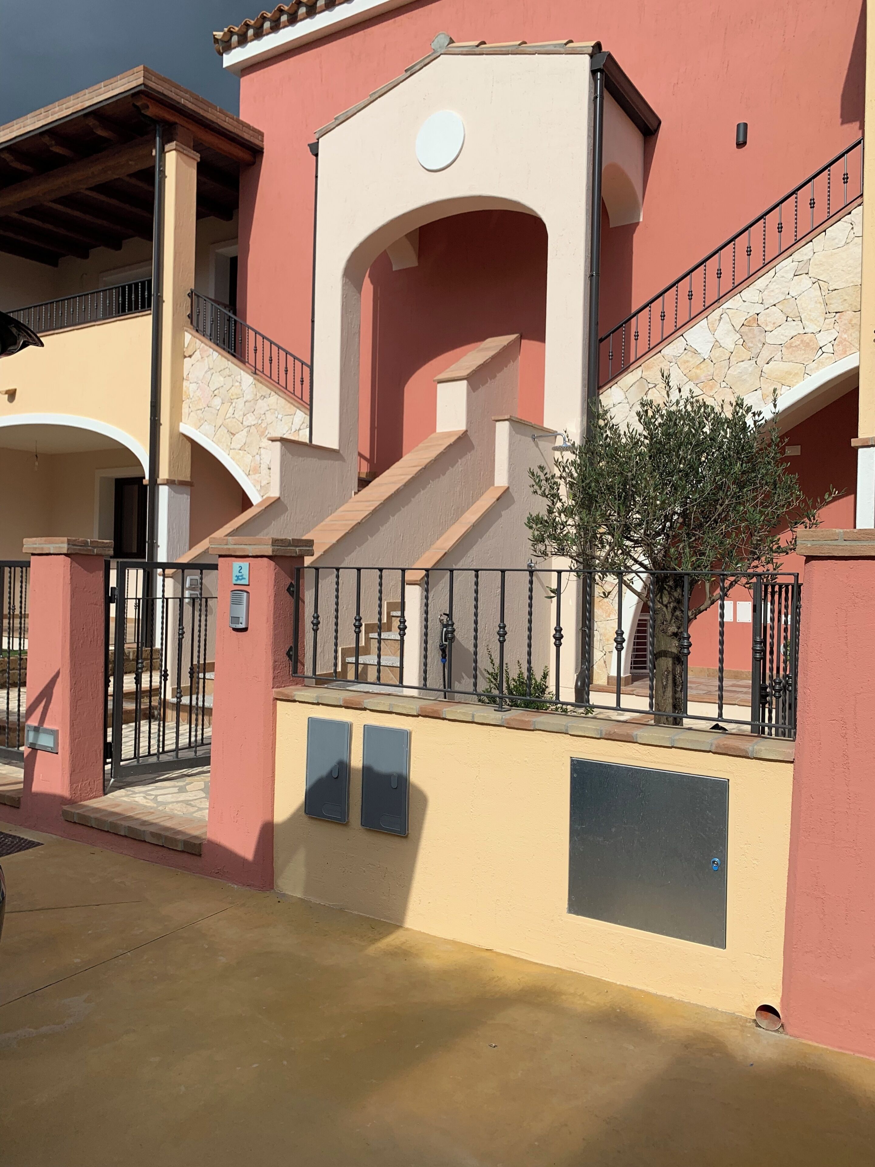 A building with a pink facade, a stone staircase, and a metal railing.