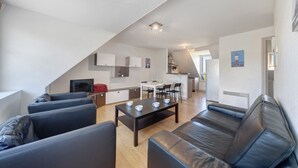 Una sala de estar moderna con un sofá de cuero negro, una mesa de centro y un comedor con una mesa y sillas blancas.