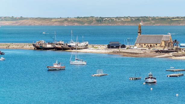 Un puerto con barcos, un faro y un edificio de techo inclinado.