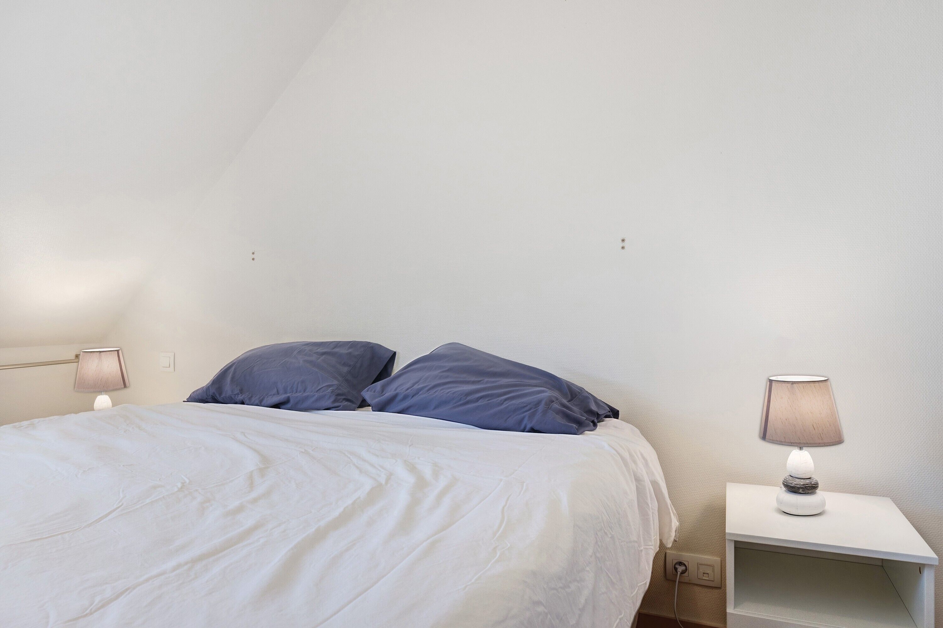 Une chambre à coucher avec un lit, deux lampes de chevet et une table de nuit.