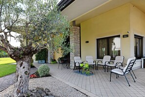 Un área de patio al aire libre con chimenea de piedra, asientos exteriores y un árbol grande.