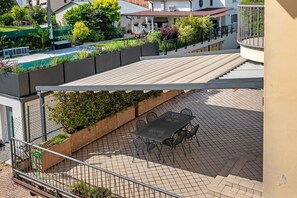 Eine Dachterrasse mit Tisch und Stühlen, ein Gartenbereich mit Pflanzen und Blick auf die umliegenden Gebäude.