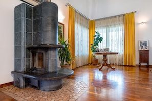 A stone fireplace, a wooden table, and yellow curtains in a room with wooden flooring.