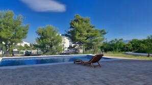 Una piscina con una sedia a sdraio, circondata da alberi ed edifici.