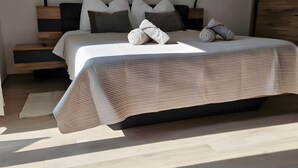 Una camera da letto moderna con un letto, cuscini, un comodino e una testata imbottita in legno.