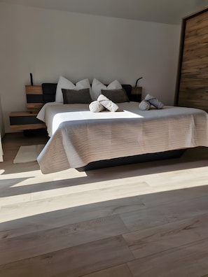 Een moderne slaapkamer met een bed, kussens, een nachtkastje en een houten hoofdbord.