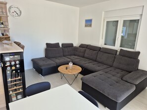Ein modernes Wohnzimmer mit einer Eckcouch, einem kleinen runden Tisch und einem Weinkühlschrank.