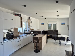 Een moderne keuken met witte kasten, een centraal eiland en een zithoek met een bank en stoelen.