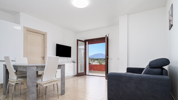 Un soggiorno moderno con zona pranzo, TV a schermo piatto e divano.