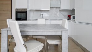 Una cucina moderna con mobili bianchi, un piano di lavoro in marmo e un forno integrato.