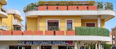 A multi-story building with a pizzeria named 'De'Avu Ristorante Pizzeria' on the ground floor.