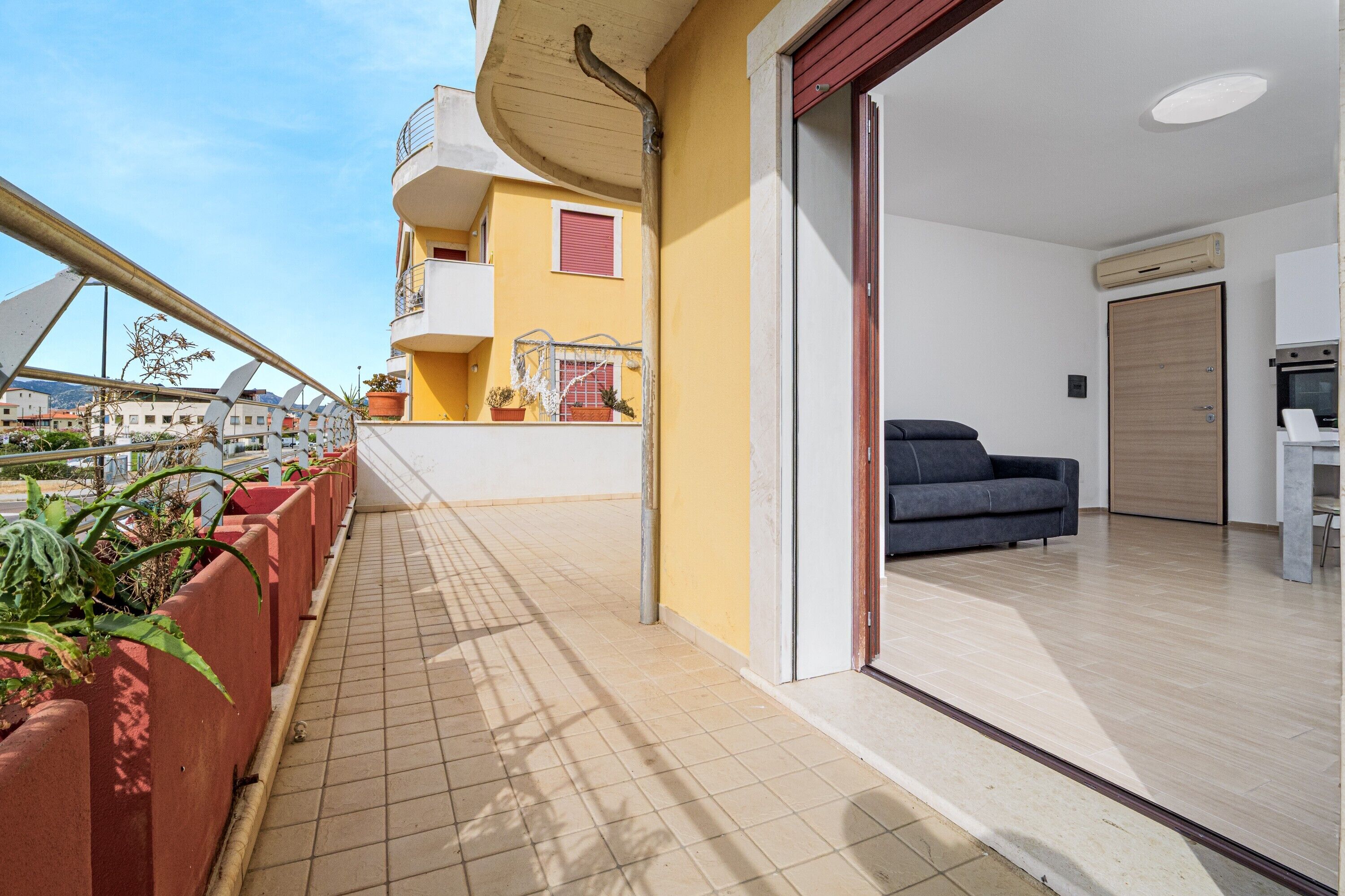 Een modern appartement met balkon, een bank en een keuken.