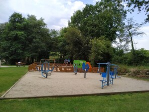 Ein Spielplatz mit Sportgeräten, einer Bank und einem eingezäunten Bereich.