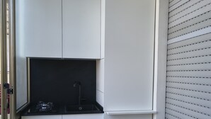 Eine kleine Küche mit weißen Schränken, einer schwarzen Arbeitsplatte und einem sichtbaren Spülbecken.