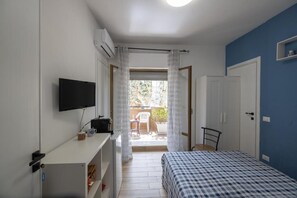A bedroom with a bed, a TV, a desk, and a balcony with a chair. - Una Terrazza nel Sole a Trapani (Trapani)