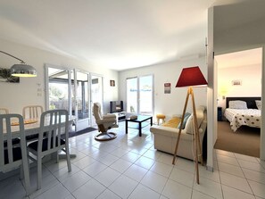 Ein modernes Wohnzimmer mit Essbereich, einer Couch, einem Fernseher und einer Lampe.