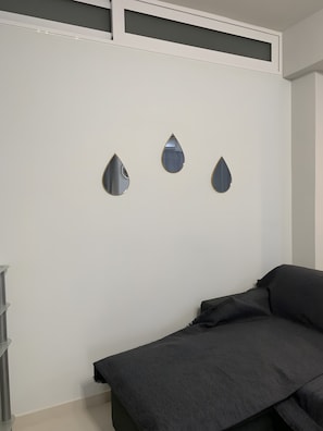 Ein Schlafzimmer mit einem Bett, einem Kleiderschrank und drei Spiegeln an der Wand.